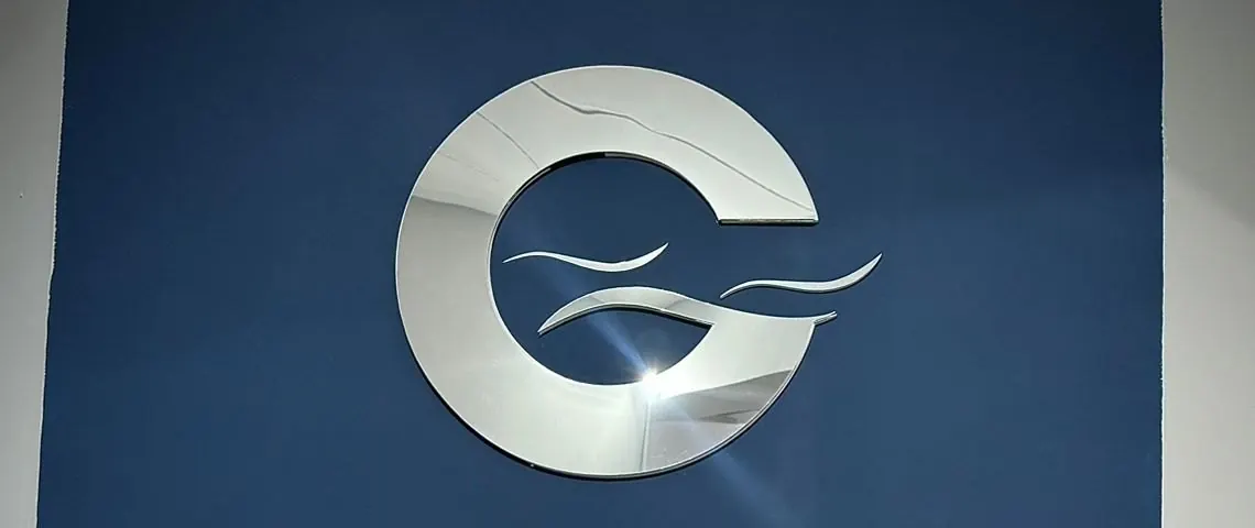 Logo da Cabral em aço escovado na parede azul do escritório